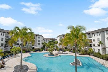 A large swimming pool with palm trees in front of some apartment buildings